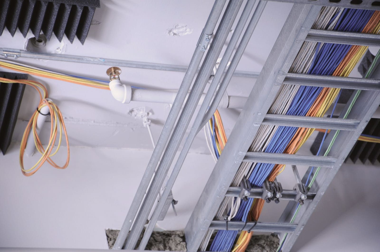 Overhead metal cable trays running through a technical space